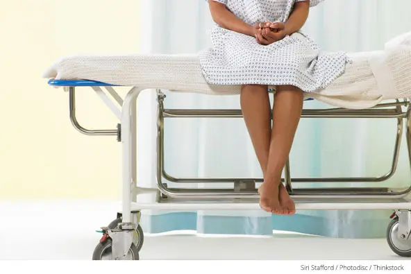 Female patient sitting on gurney in hospital gown
